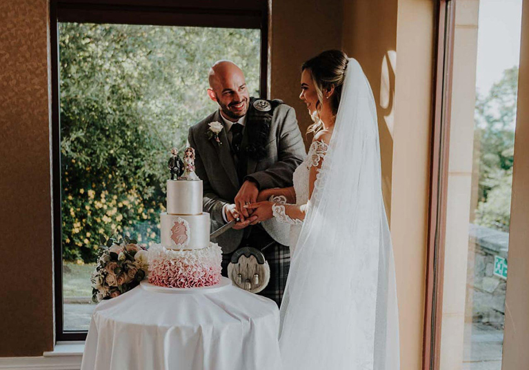 Bride and groom cutting cake and smiling